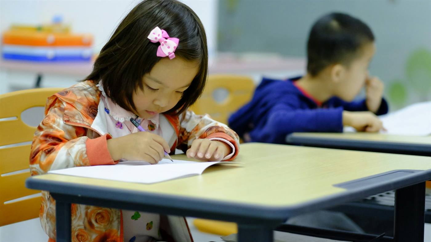 机に向かって学ぶ子ども